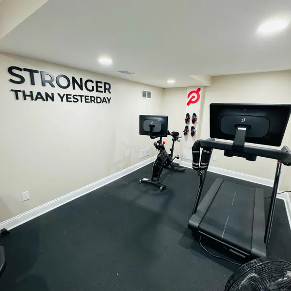 STRONGER THAN YESTERDAY lettering in a customer's gym with an exercise bike and treadmill