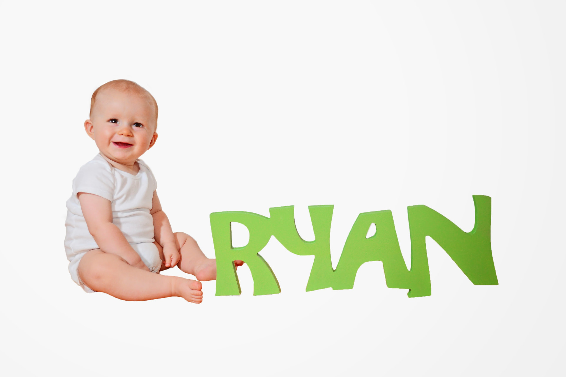 Our first son sitting beside the green letter name sign we made for his nursery