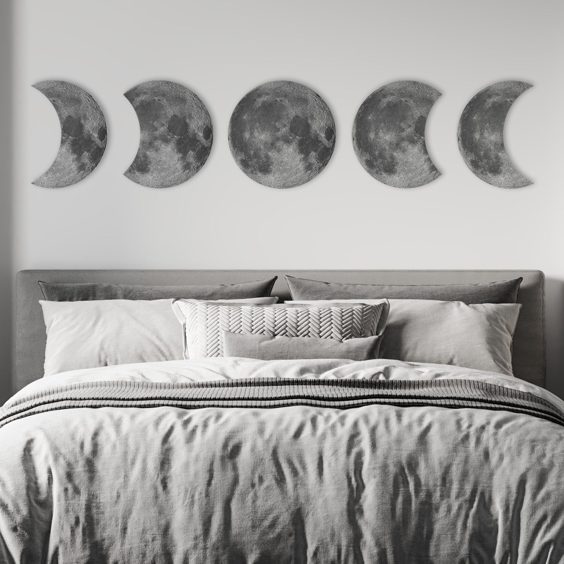 Moon phases wall decor displayed above bed in modern bedroom, celestial wall art focal point